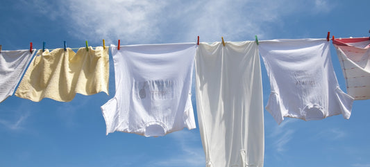 An einer Wäscheleine im Freien ist frische Wäsche unter blauem Himmel aufgehängt.
