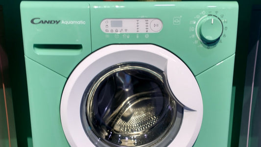 Miniatur Waschmaschine in Grün mit aufgemalter Dekoration. Die Dekoration erinnert an ein Kinderspielzeug.