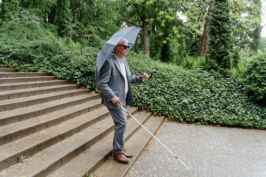 Blinder Mensch versucht sich auf einer Treppe zu orientieren und sie herunterzulaufen.