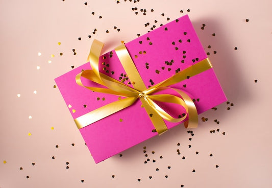 Ein Geschenk mit pinkem Geschenkpapier und einer goldenen Schleife.