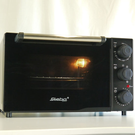 Der Mini-Backofen ist schwarz. Der Türgriff an der Oberseite öffnet nach vorne. Rechts befinden sich drei Drehknöpfe zur Bedienung.